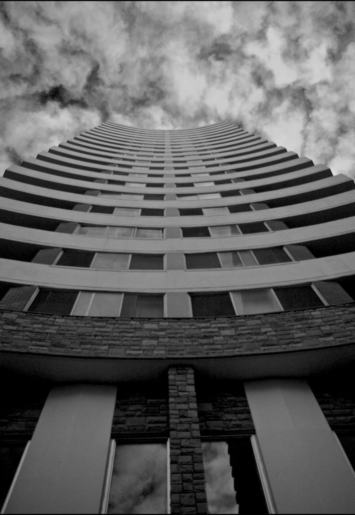 curving elevation of apartment tower with clouds