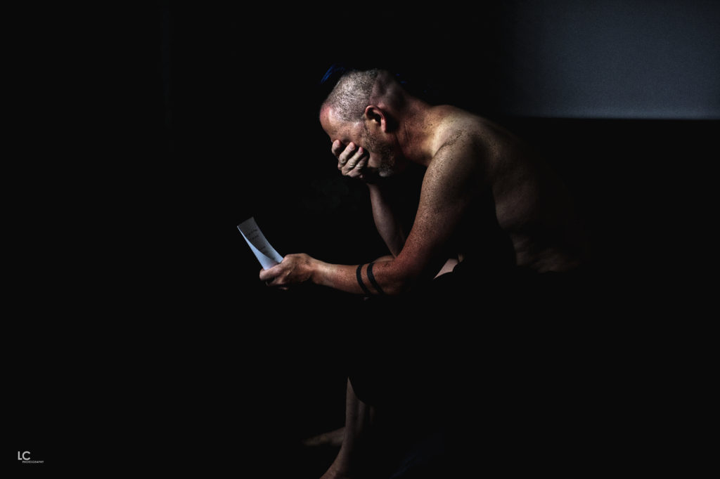Male sitting in dark room reading note
