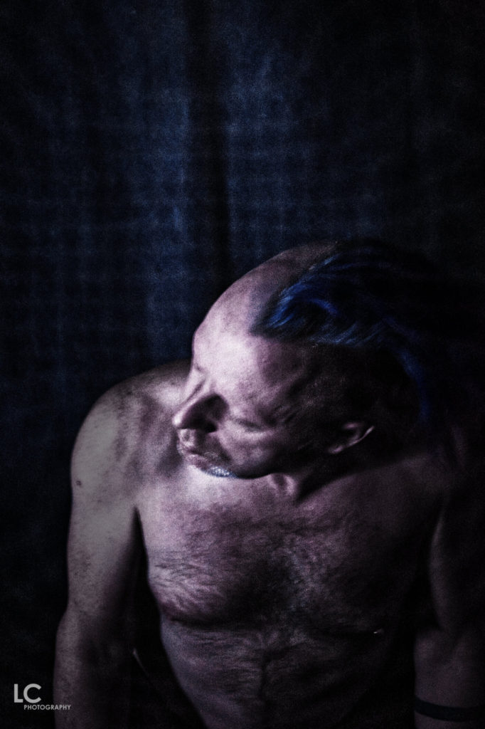 Shirtless male leaning forward with head turned to side