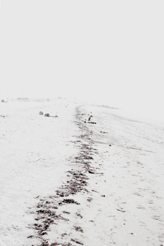 High tide line on beach leading towards empty horizon