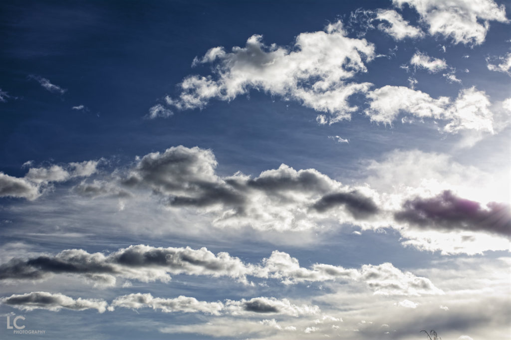 scattered cloud against blue sky with sunflare coming in from the side