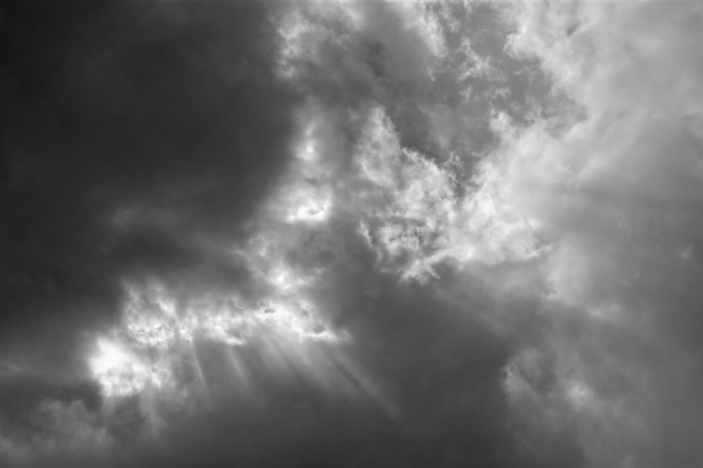 Rays of light shining through layered storm clouds