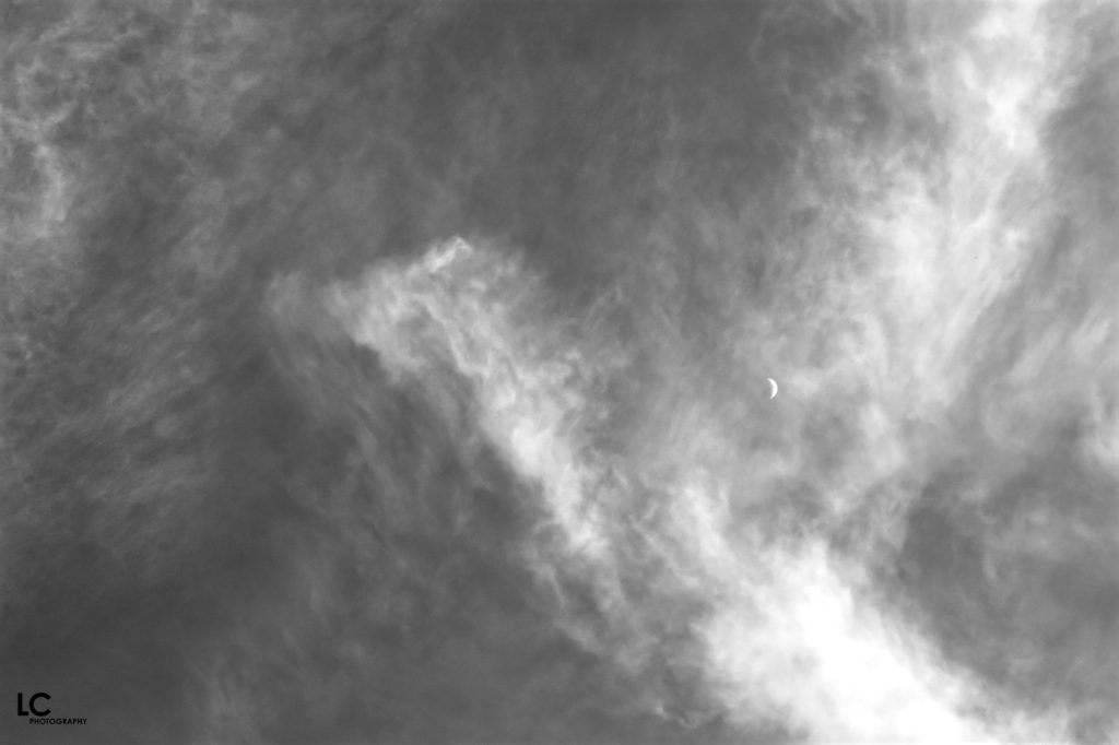 Thin, high cloud with waning moon visible through the cloud